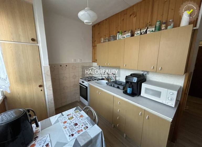 Küche in einer 2-Zimmer-Wohnung mit Holzdekor, einschließlich Geräten und Esstisch.