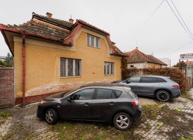 Ein Einfamilienhaus in der Partizánska-Straße in Bánovce nad Bebravou mit zwei Autos, die davor geparkt sind.