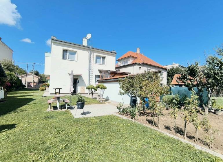 Ein Einfamilienhaus in Partizánske, umgeben von einem grünen Rasen und einem Garten unter blauem Himmel.