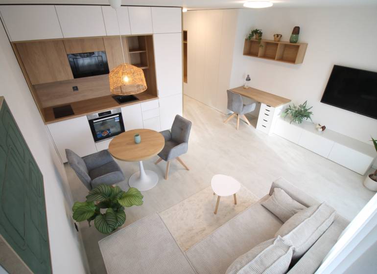 Innenraum einer 1-Zimmer-Wohnung mit Küche, Esstisch und Arbeitsecke.