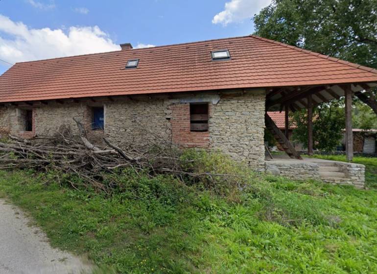 Eine Hütte in Zliechov mit steinernen Wänden und einem schrägen roten Dach.