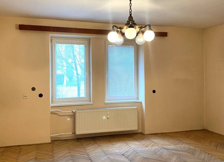 Ein Zimmer in einer 2-Zimmer-Wohnung mit einem Holzboden und einem hängenden Kronleuchter.