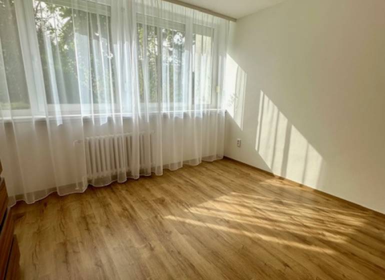 Ein Zimmer in einer 3-Zimmer-Wohnung mit einem Holzboden und einem großen Fenster.