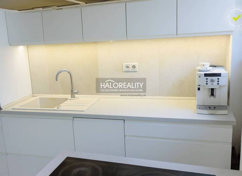 Eine Küche mit weißen Schränken und einer Kaffeemaschine in einer 3-Zimmer-Wohnung.