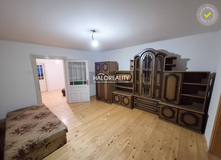 Ein Zimmer in einem Einfamilienhaus mit Möbeln und einem Boden in Holzoptik.