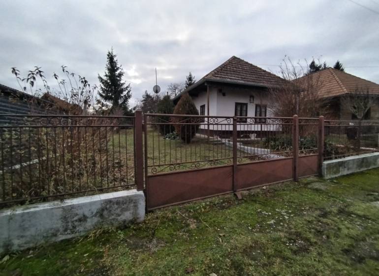 Ein Einfamilienhaus in Dolný Pial, umgeben von einem Garten und einem Zaun, bei bewölktem Wetter.