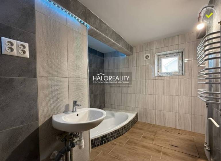 Badezimmer eines Einfamilienhauses mit Badewanne, Waschbecken und Boden mit Holzdekor.