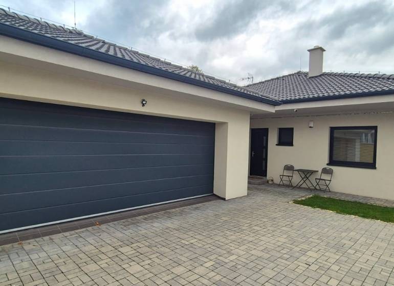 Ein Einfamilienhaus in Studienka mit zwei Stühlen und einem Tisch auf dem gepflasterten Hof.