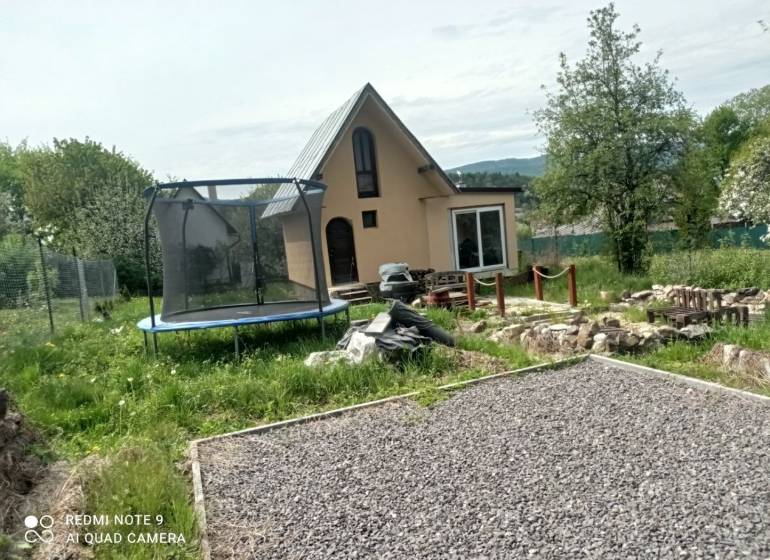 Eine Hütte in Hliník nad Hronom mit einem Trampolin und einem steinigen Weg im Garten.