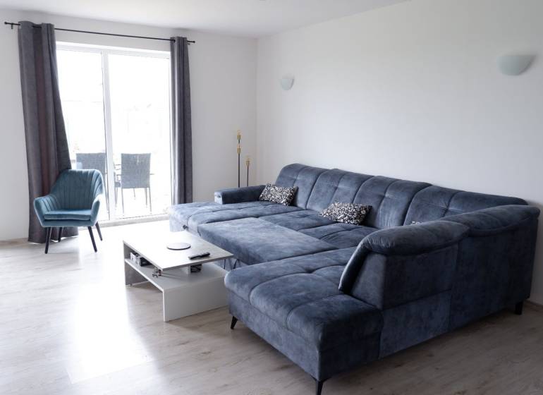 Wohnzimmer mit blauer Couch und Sessel, Holzboden, Einfamilienhaus.