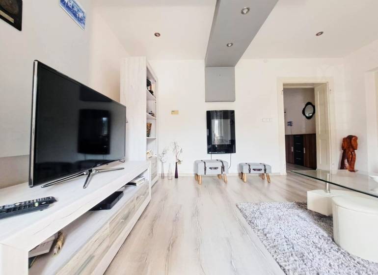 Wohnzimmer in einem Einfamilienhaus mit Fernseher und Holzboden.