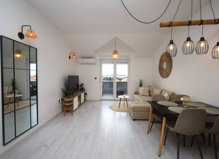 Wohnzimmer in einer Ferienwohnung mit Holzboden und großem Spiegel.