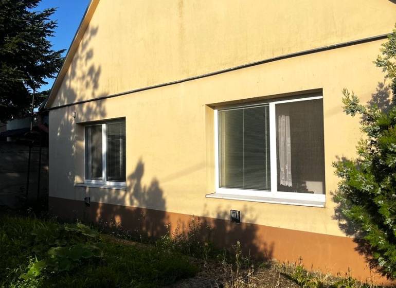 Ein Einfamilienhaus in Diakovce mit einem schrägen Dach und einer gelben Fassade, umgeben von Grün.