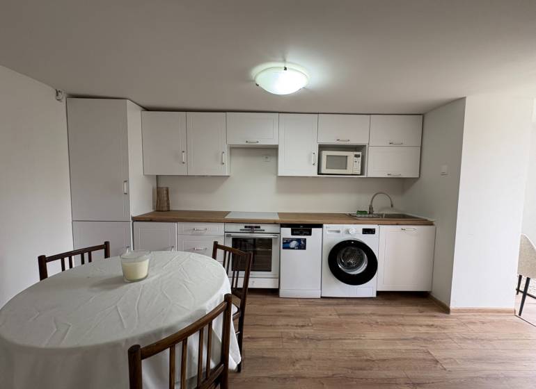 Küche in einer Einzimmerwohnung mit weißen Schränken und einem Boden in Holzoptik.