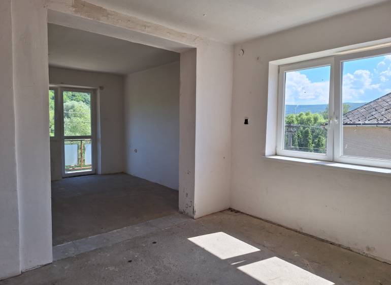 Izba v einem Einfamilienhaus, große Fenster, Blick auf den Garten und die umliegenden Bäume.