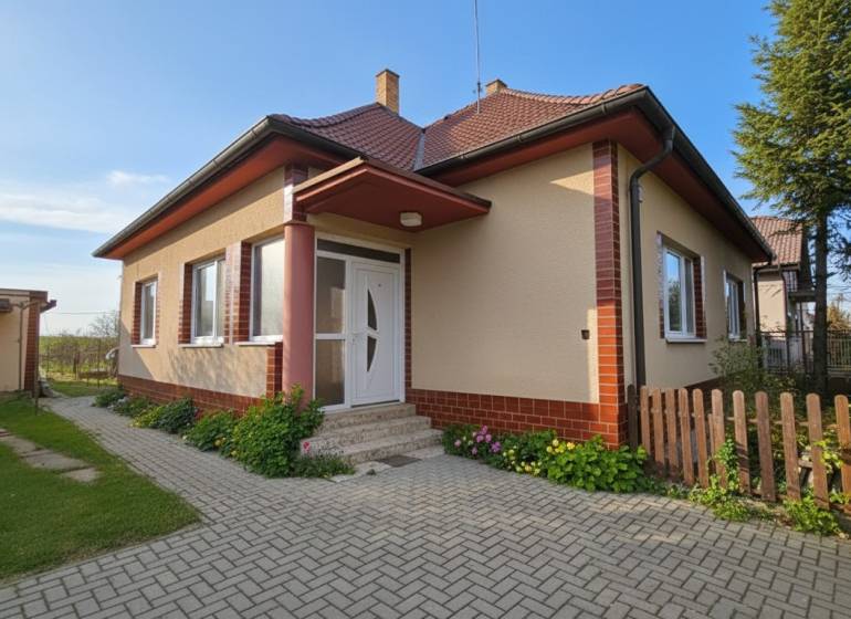 Ein Einfamilienhaus in Križovany nad Dudváhom mit einem gepflegten Garten und einem gepflasterten Gehweg.