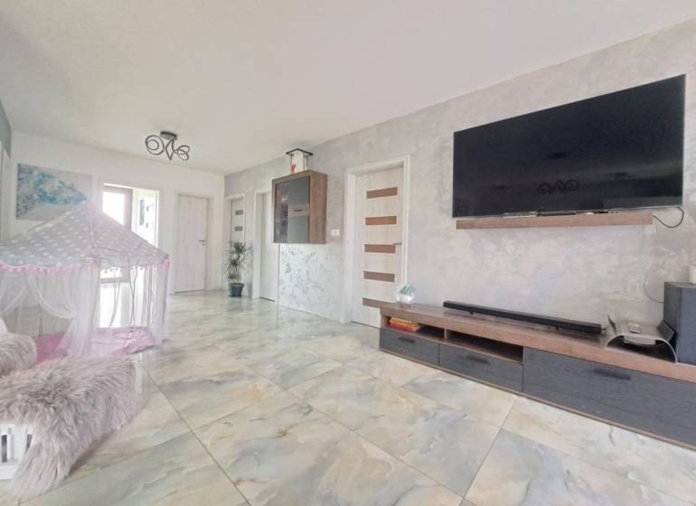 Wohnzimmer in einem Einfamilienhaus mit einem Fernseher an der Wand, einem Zelt und einem Keramikboden.