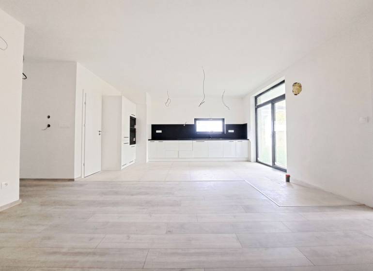 Geräumige Küche mit schwarzen Fliesen und Boden in Holzoptik in einem Einfamilienhaus.