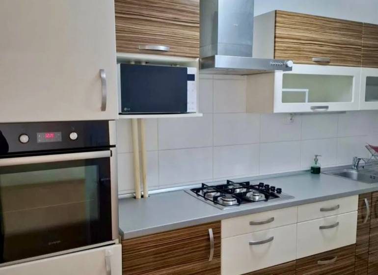 Küche mit Steinspüle, Kochfeld und Dunstabzugshaube in einer 4-Zimmer-Wohnung.