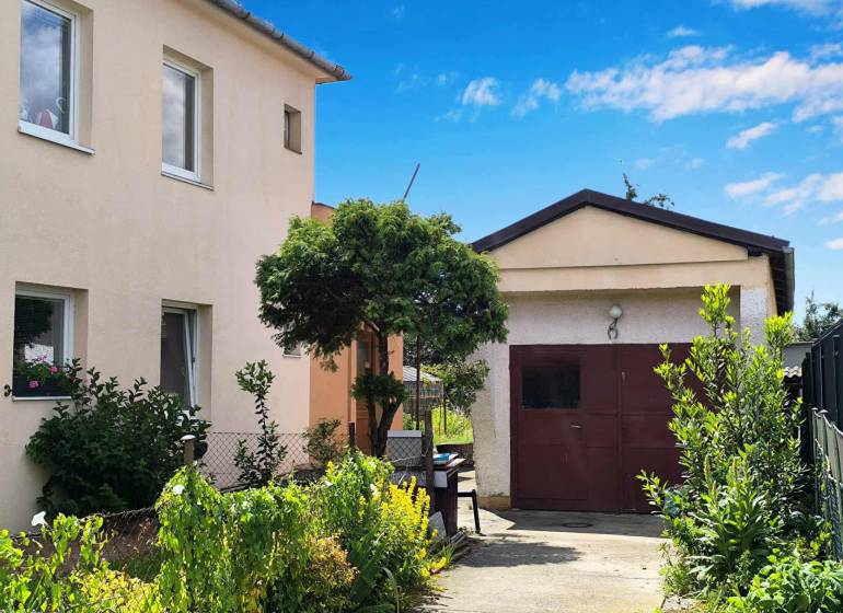 Ein Einfamilienhaus in Partizánske mit Garage, umgeben von einem Garten voller grüner Pflanzen.