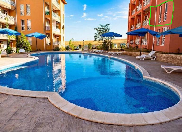 Ferienwohnung in Burgas mit Pool, Liegestühlen und Sonnenschirmen auf der gepflasterten Terrasse.