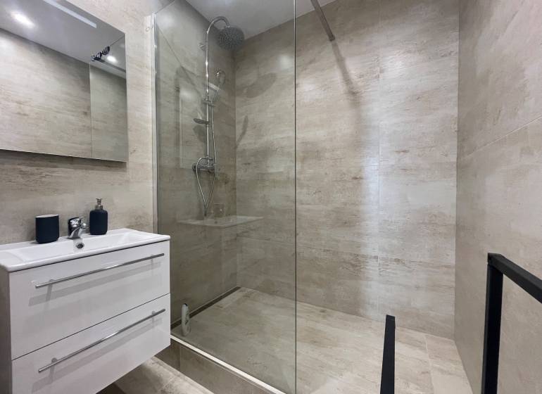 Badezimmer in einer 3-Zimmer-Wohnung mit Duschkabine und Stauraum unter dem Waschbecken.