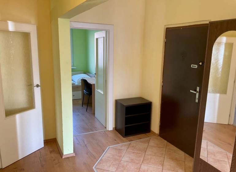 Flur mit dunklen Türen, Boden mit Holzdekor, Blick ins Zimmer.