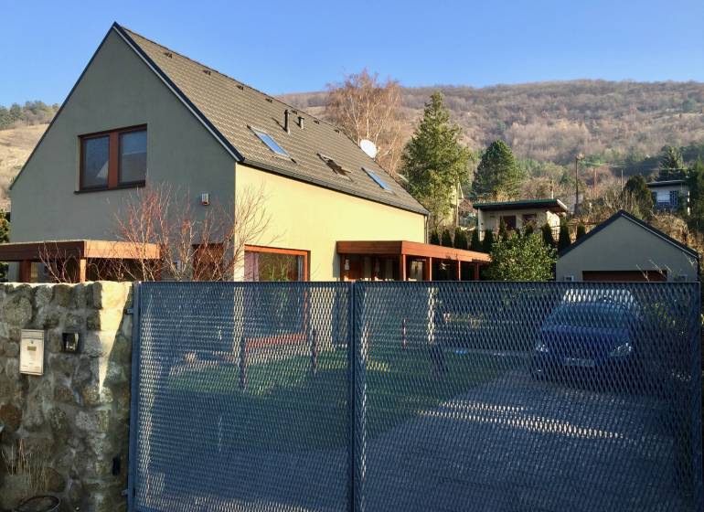 Ein Einfamilienhaus in der Kremeľská-Straße in Bratislava - Devín, umgeben von einem Garten und Bergen.