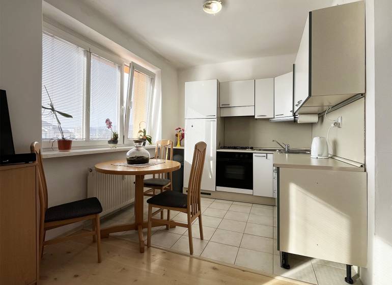 Küche in einer Einzimmerwohnung mit rundem Tisch und Holzboden.