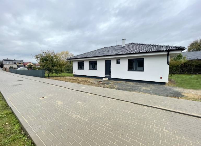 Ein Einfamilienhaus in der Gemeinde Soľ mit einer weiß-grauen Fassade, umgeben von einem gepflasterten Gehweg.