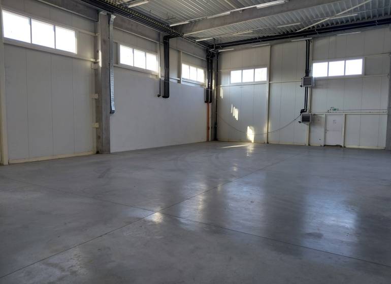 Pohľad do prázdnej haly so svetlými stenami v skladoch a halách.