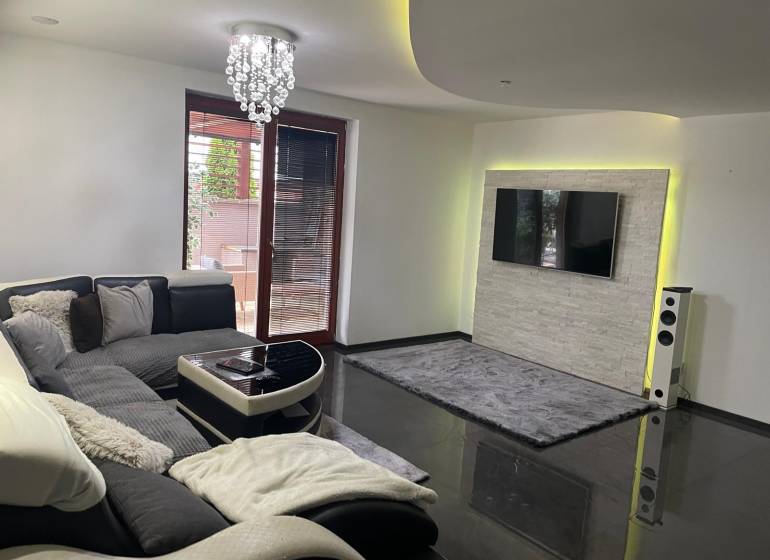 Wohnzimmer in einem Einfamilienhaus mit Sofa und Fernseher an der Wand mit Steinverkleidung.