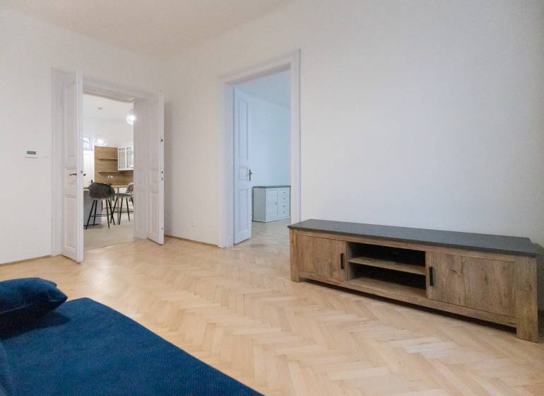 Wohnzimmer einer 3-Zimmer-Wohnung mit einem blauen Sofa und einem Boden in Holzoptik.