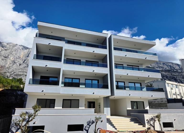 Ferienwohnung in Makarska, Gebäude mit vier Etagen und Balkonen, Bergkulisse.