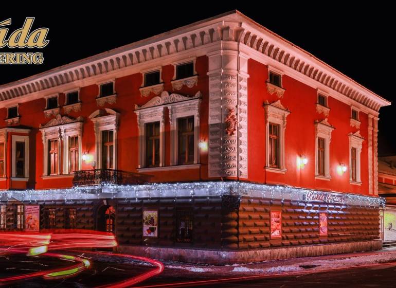 Ein beleuchtetes Hotelgebäude mit roter Fassade in Poprad. Hotels und Pensionen.