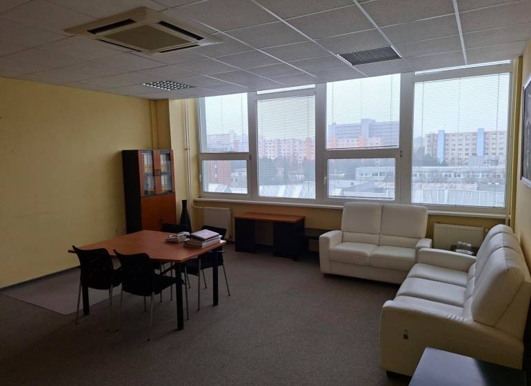 Geräumiges Büro mit Sofas, Tisch und Fenstern mit Blick auf die Stadtsilhouette.
