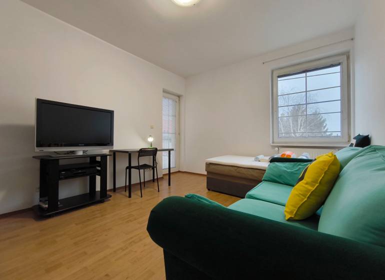 Wohnzimmer in einem Einfamilienhaus mit Sofa, Fernseher, Tisch und Holzboden.