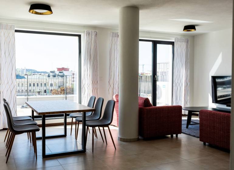 Wohnzimmer in einer 3-Zimmer-Wohnung mit Esstisch und Blick auf die Stadt.