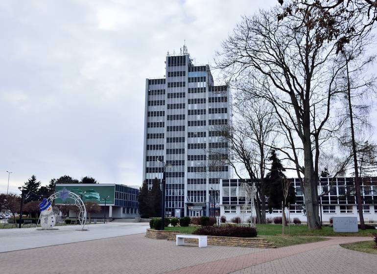 Büros am Freiheitsplatz in Michalovce, ein hohes Gebäude mit Fenstern und Bäumen in der Umgebung.