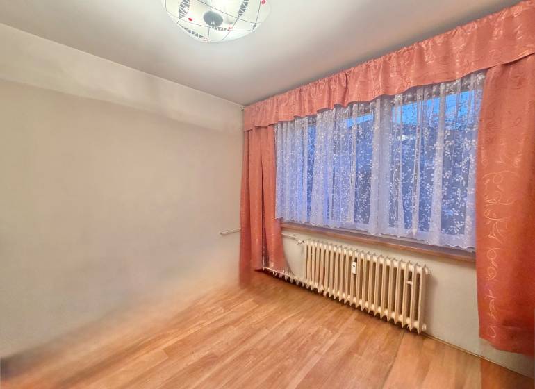 Ein Zimmer in einer 3-Zimmer-Wohnung mit einem Boden in Holzoptik und Vorhängen.