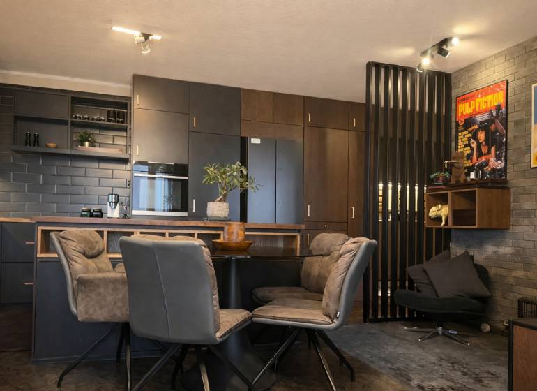 Küche in einer 2-Zimmer-Wohnung mit dunklen Schränken und dekorativen Postern an der Wand.