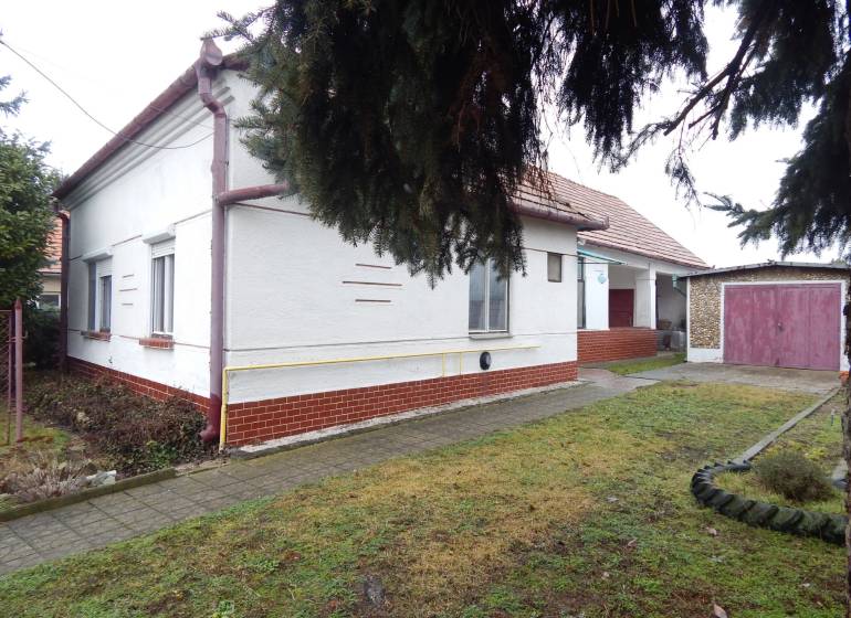 Einfamilienhaus in Kravany nad Dunajom mit Garage, daneben Gehweg und Rasenfläche.