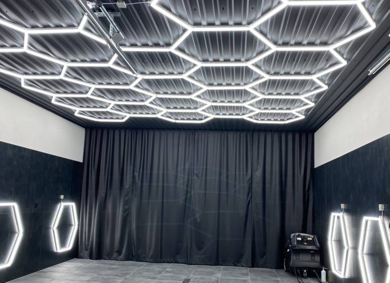 Geschäftsräume mit dunklem Dekor und sechseckiger LED-Beleuchtung an Decke und Wänden.