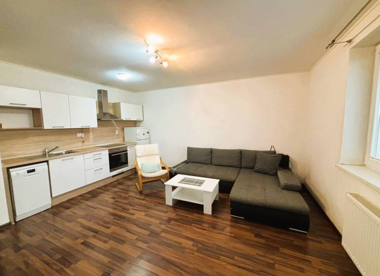 Wohnzimmer in einer 2-Zimmer-Wohnung mit einer Eckcouch und einer Küchenzeile.