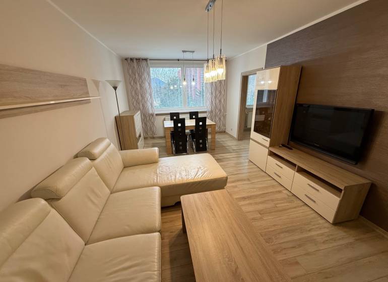 Wohnzimmer mit Holzboden, großem Sofa und Esstisch in einer 3-Zimmer-Wohnung.