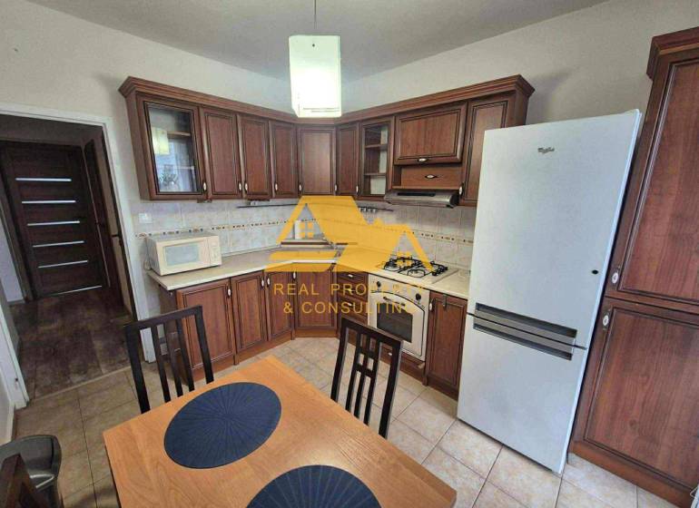 Küche mit dunklem Holzdekor, Herd und Kühlschrank in einer 3-Zimmer-Wohnung.