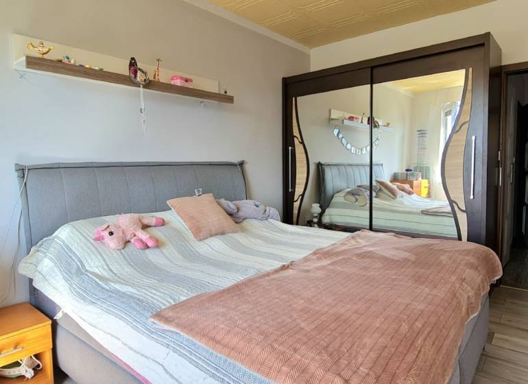 Schlafzimmer in einer 2-Zimmer-Wohnung mit einem Spiegelschrank und einem gepolsterten Bett.