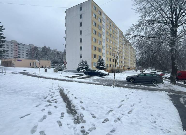 Winterszene in der Bazovského-Straße in Zvolen mit einem Plattenbau und geparkten Autos.