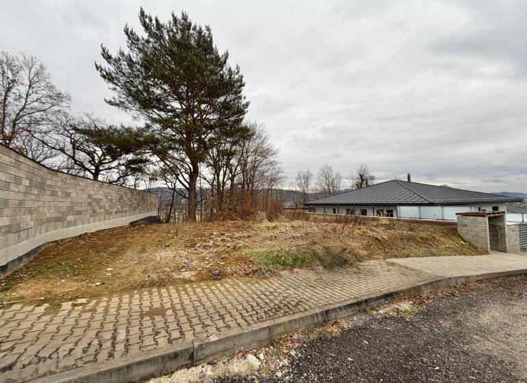 Baugrundstück in Groß-Bytča in der Stadt Bytča mit Gehweg und Bäumen.