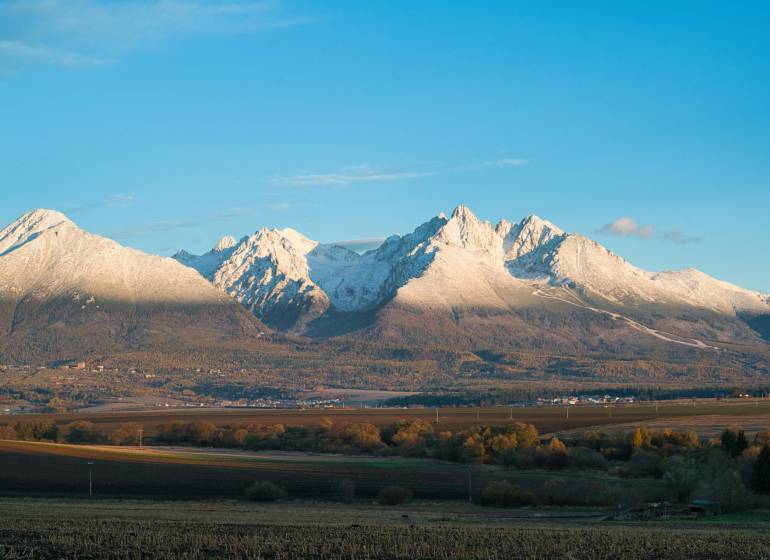 Schneebedeckte Gipfel, herbstliche Landschaft und landwirtschaftliche sowie forstwirtschaftliche Flächen rund um Poprad.